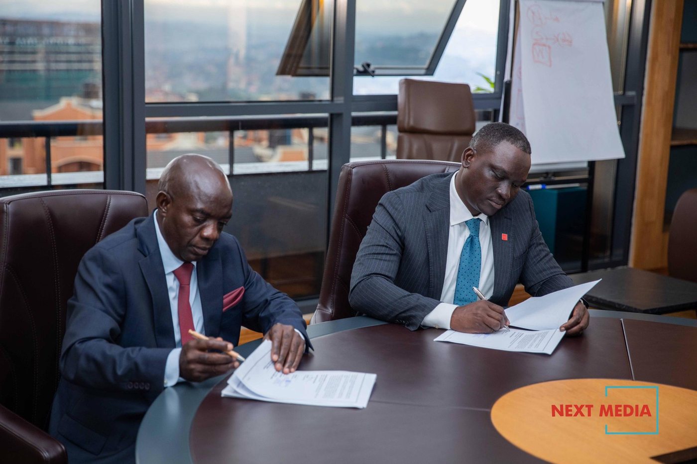Officials signing partnership documents at a Kampala office